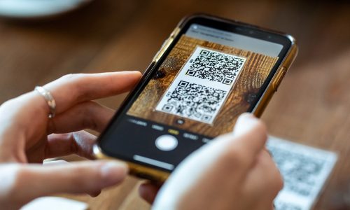 Close up of young woman hands using the smart phone to scan the qr code to select food menu in the restaurant.